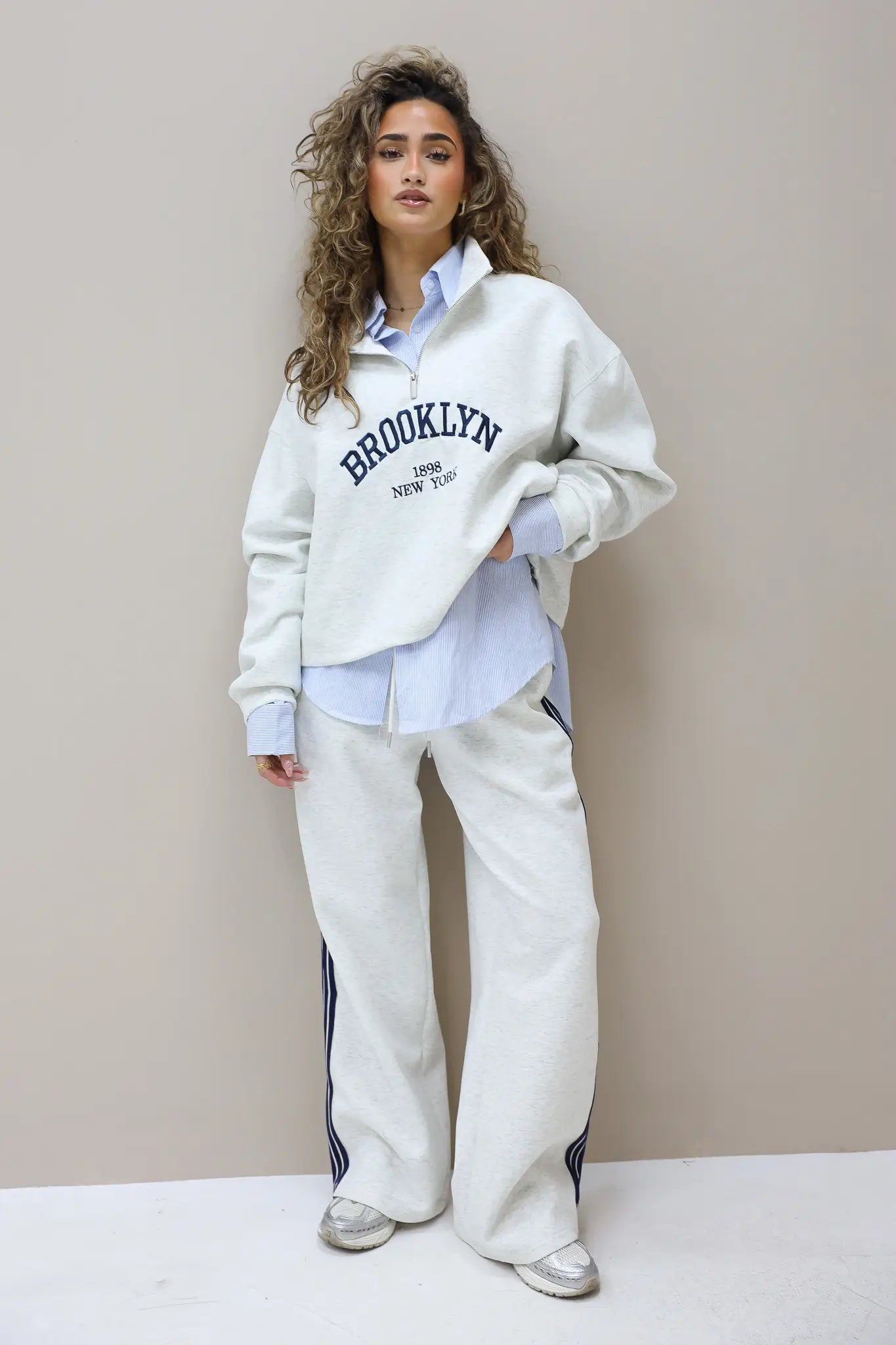 model draagt grijze sweater met rits en opdruk