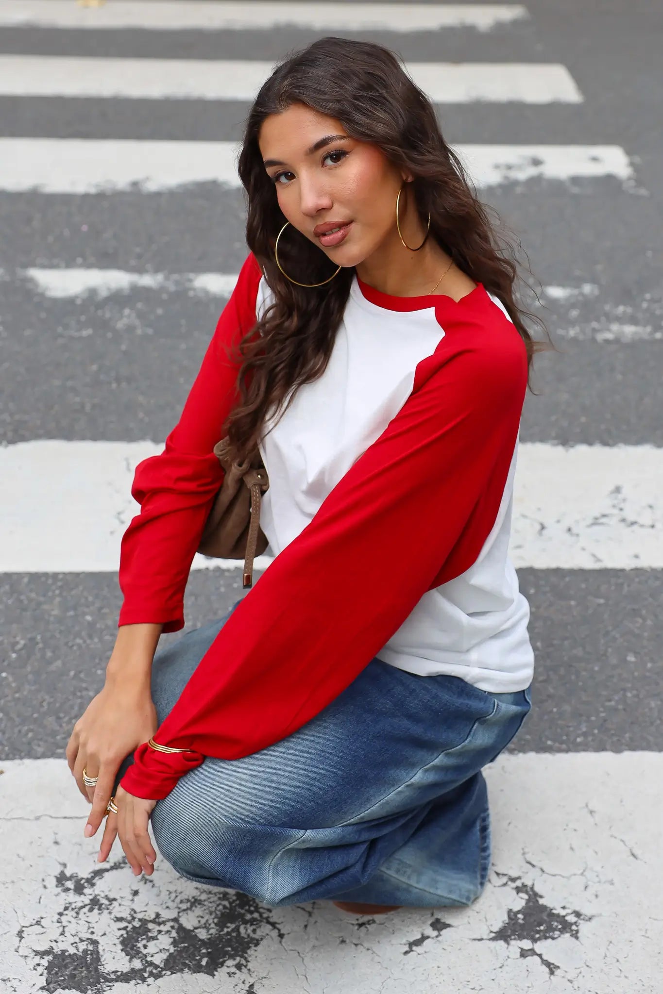 Wit T-shirt met rode raglanmouwen en ronde hals zittend op straat