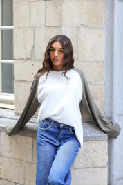 Losvallend wit shirt met taupe lange mouwen gecombineerd met blauwe jeans