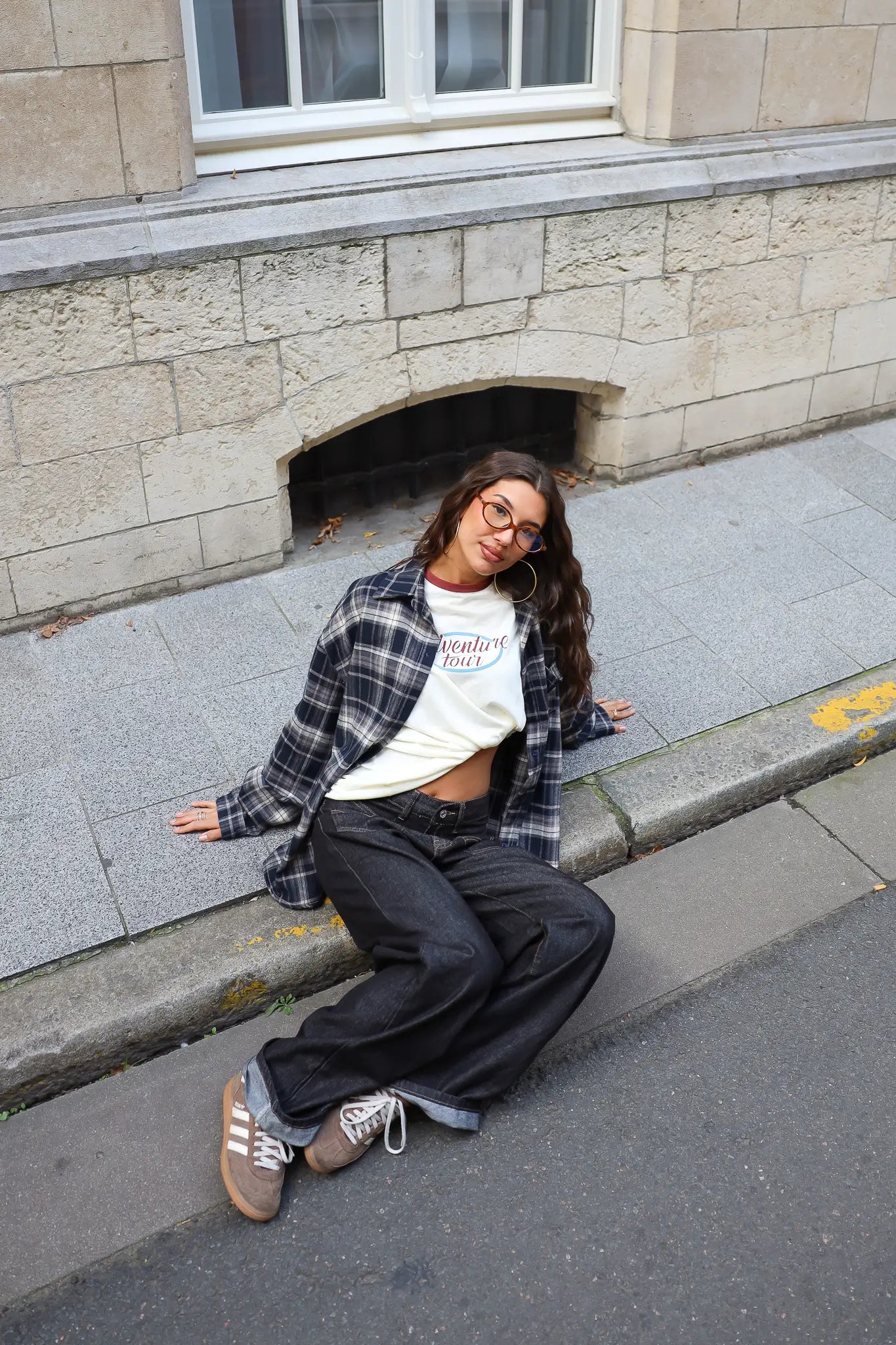 Casual outfit met crème Adventure longsleeve, donkerblauwe geruite blouse en zwarte wide leg broek.