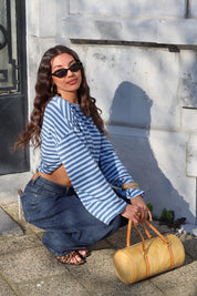 model zit met licht blauw gestreept t shirt lange mouwen en tas