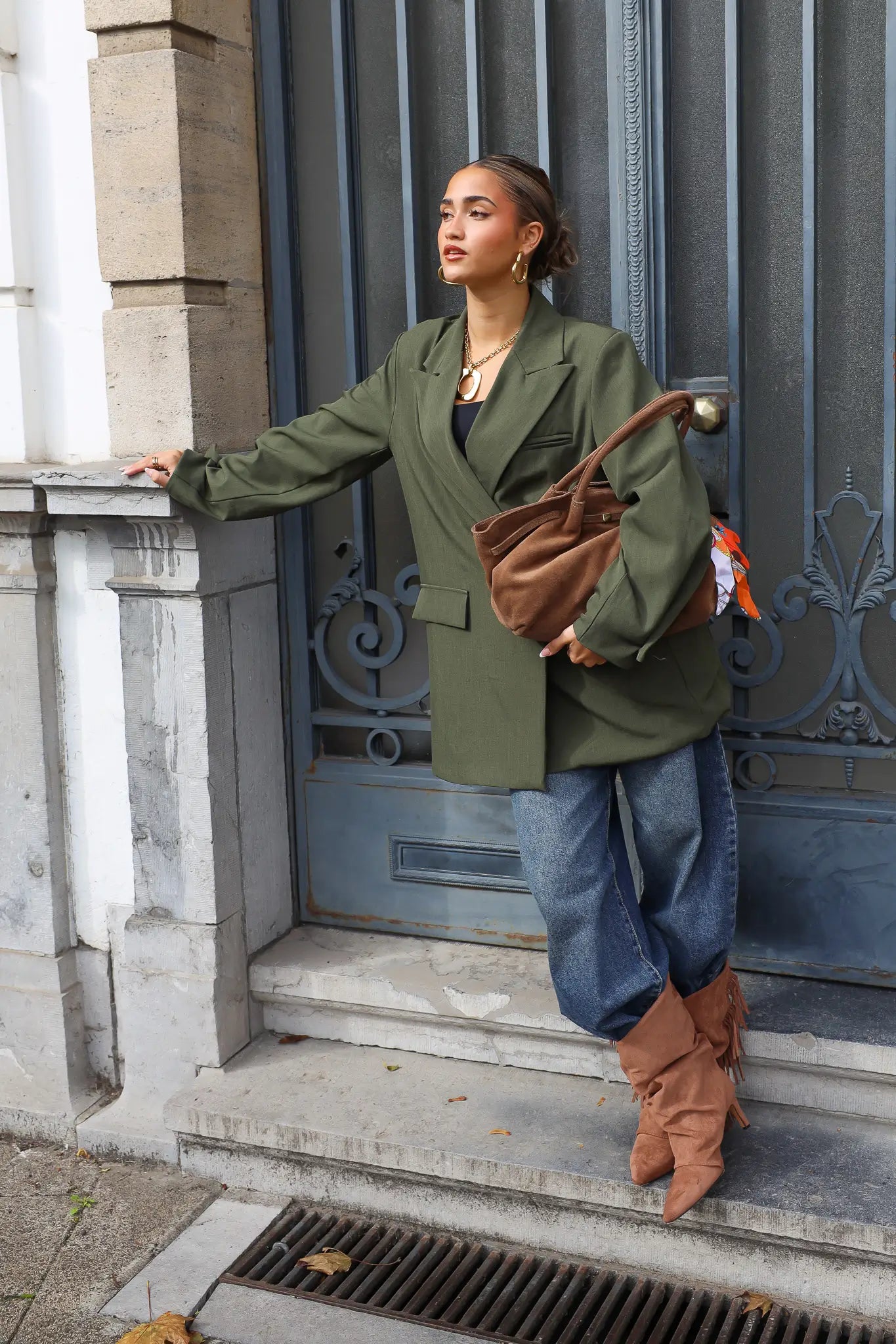 vrouw draagt taupe suède shopper over arm bij groene deur