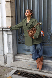 vrouw draagt taupe suède shopper over arm bij groene deur