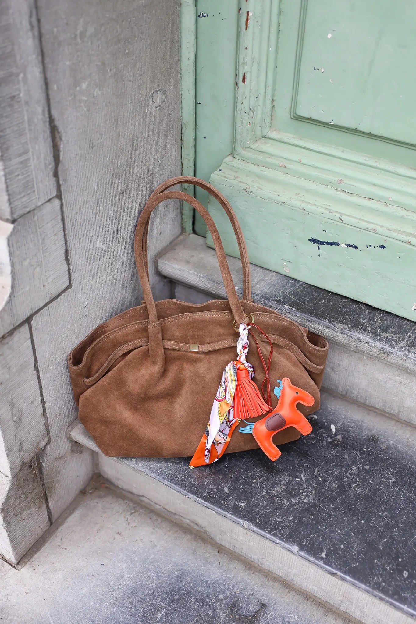 taupekleurige suède shopper gefotografeerd buiten bij groene deur