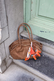 taupekleurige suède shopper gefotografeerd buiten bij groene deur