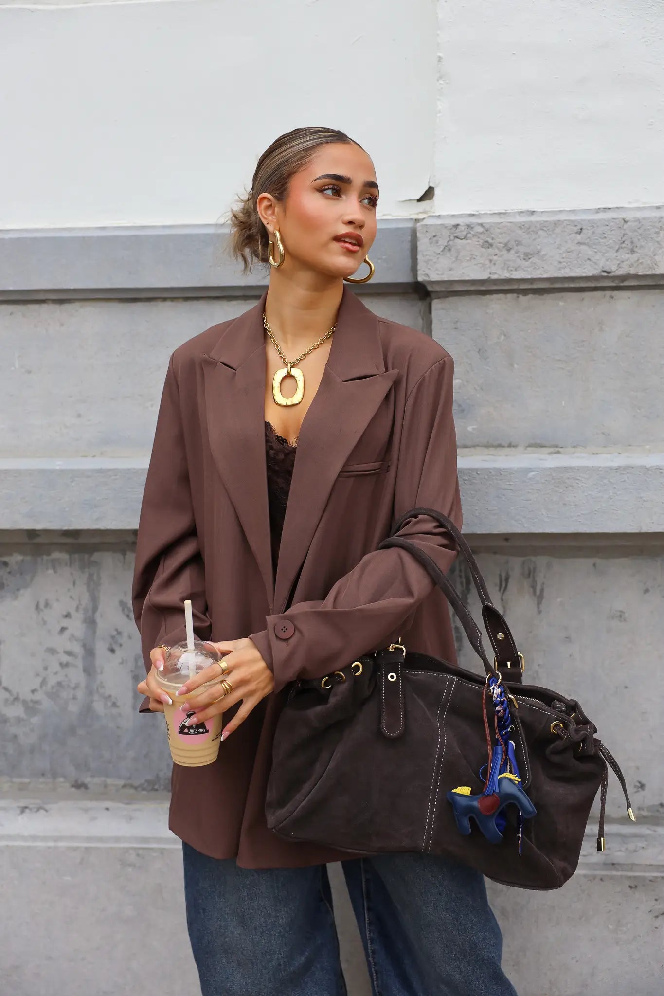 vrouw met donkerbruine suède tas in hand bij straatbeeld