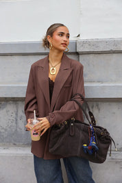 vrouw met donkerbruine suède tas in hand bij straatbeeld