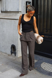 Taupe pantalon met plooien aan de voorkant en wijde broekspijpen gecombineerd met zwarte top