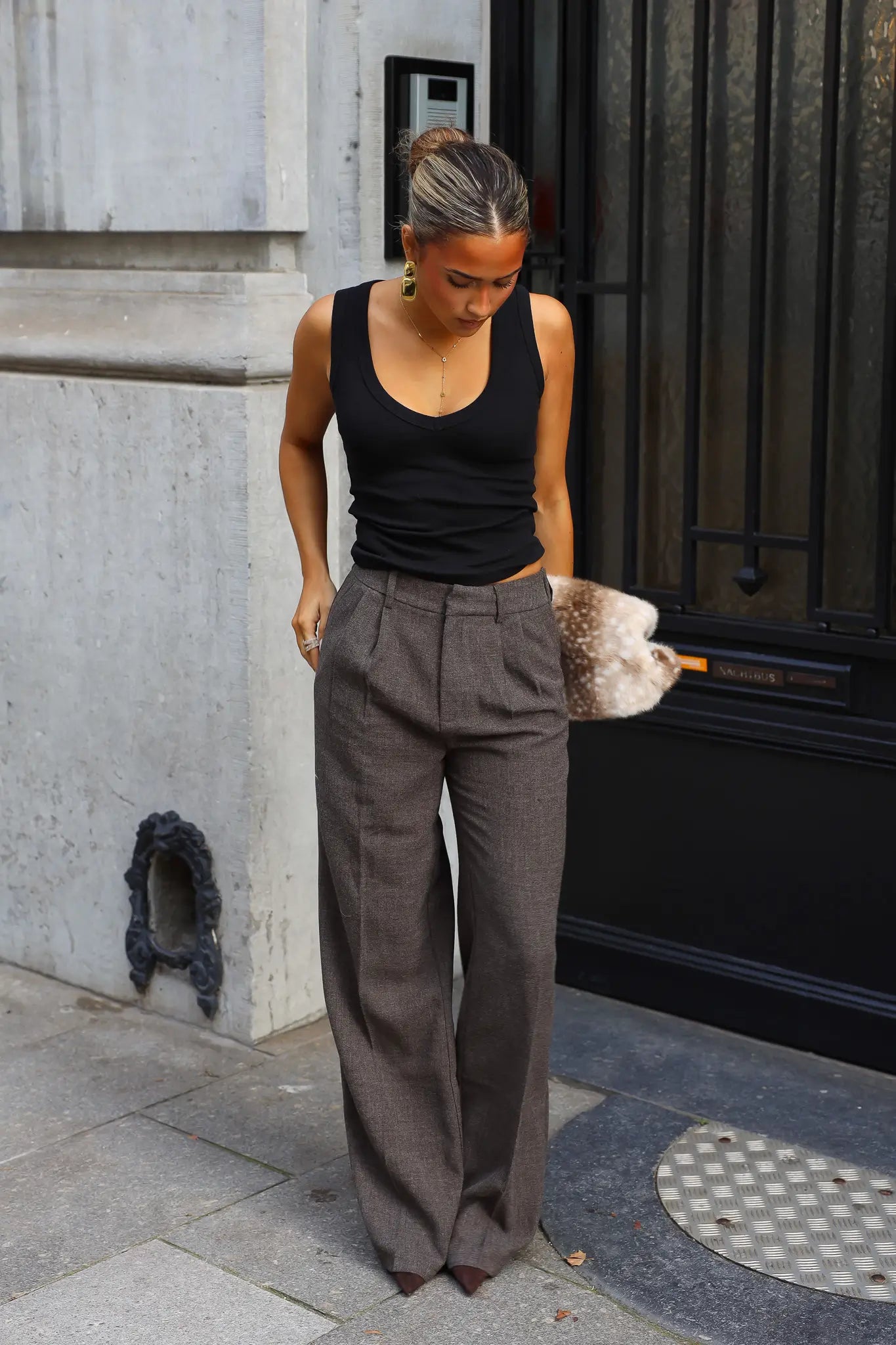 Grijsbruine wide leg pantalon met plooien en steekzakken gedragen met een zwarte mouwloze top