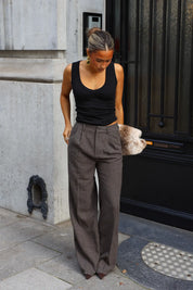 Grijsbruine wide leg pantalon met plooien en steekzakken gedragen met een zwarte mouwloze top