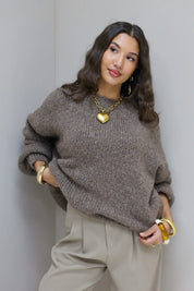 Model draagt taupe fluffy trui met beige pantalon en gouden sieraden