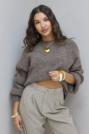 Model kijkt recht in camera in taupe fluffy trui met beige pantalon