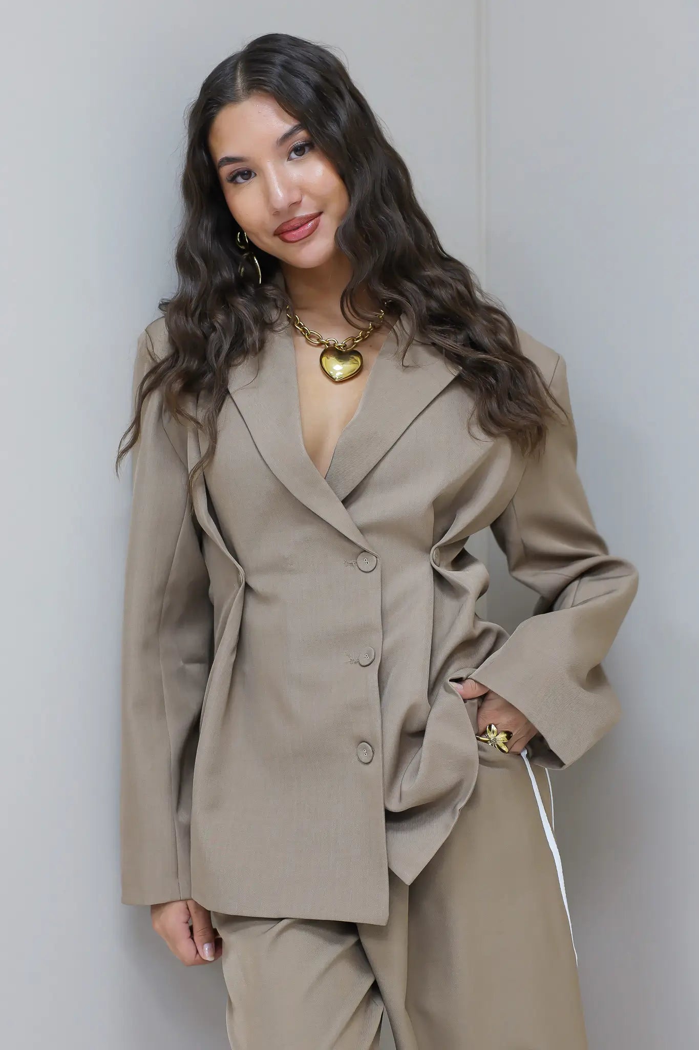 Model in taupe oversized blazer met pantalon voor neutrale achtergrond