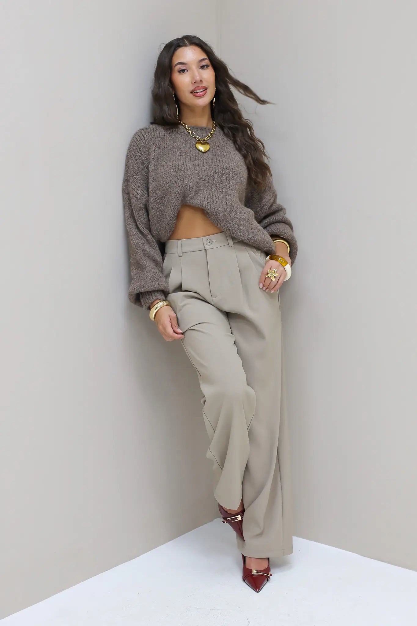 Model poseert recht in taupe pantalon met grijze trui