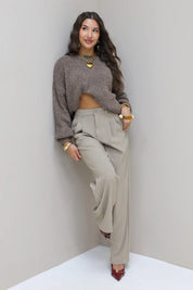 Model in taupe pantalon en grijze trui gezien vanaf de zijkant