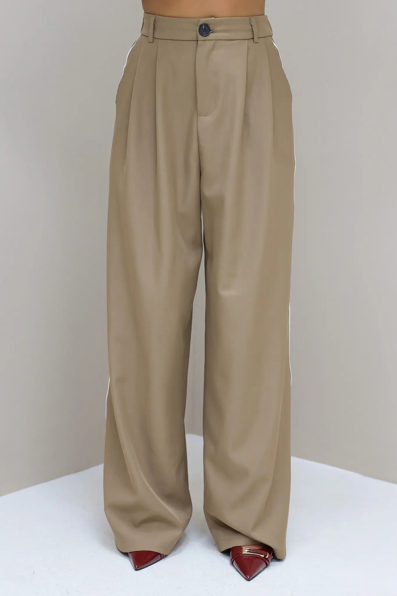 Model staat recht in taupe pantalon met witte bies en blazer