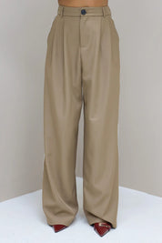 Model staat recht in taupe pantalon met witte bies en blazer