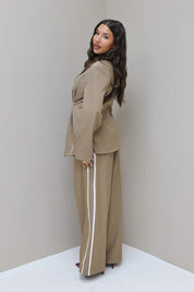 Model poseert in studio met taupe pantalon met witte bies
