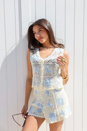 model staat tegen witte muur met gehaakte top beige blauw