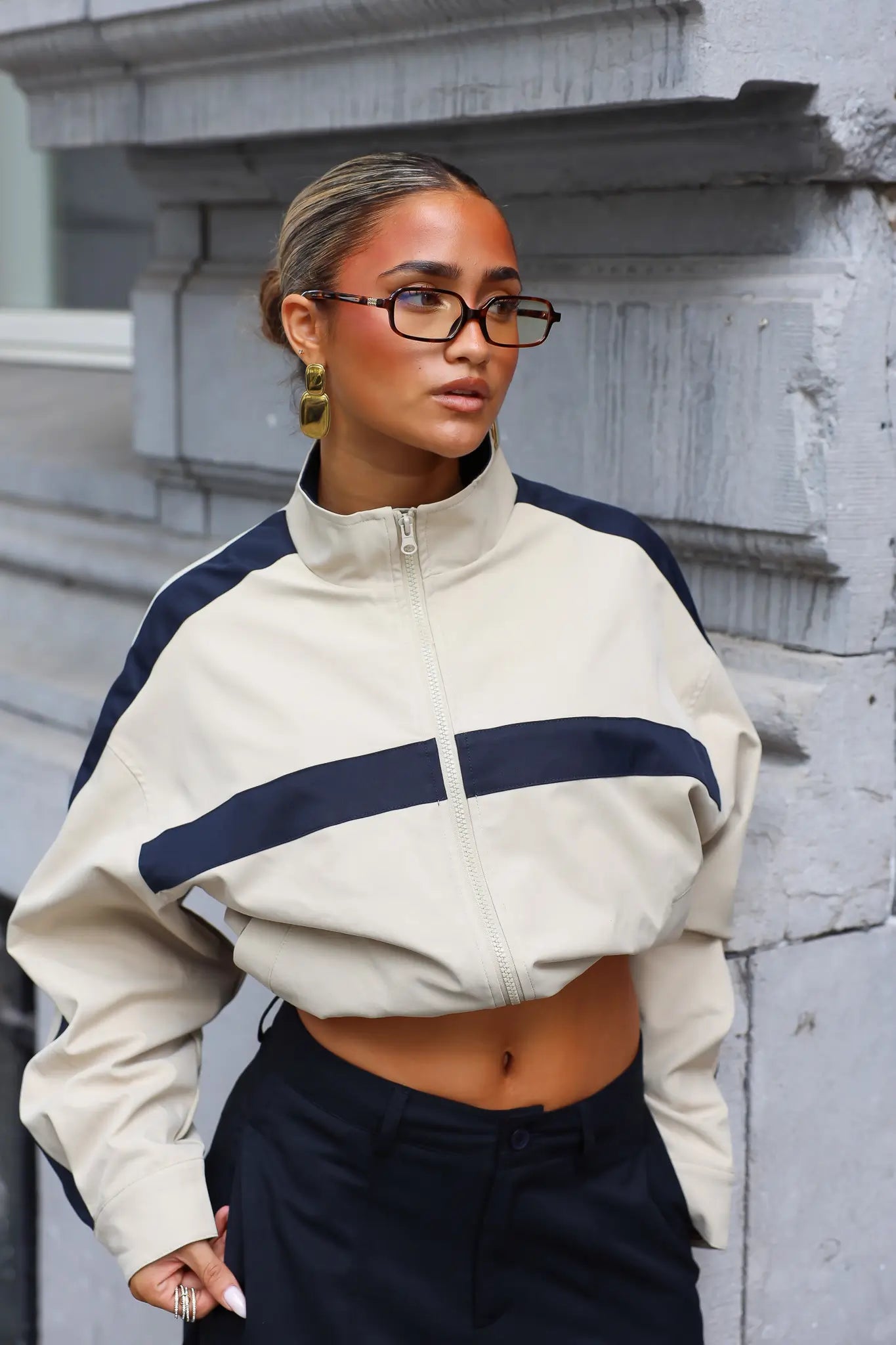 Close-up van camel track jacket met hoge ritssluiting opstaande kraag en brede donkerblauwe streep op de borst