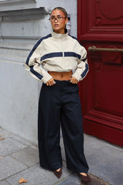 Track jas camel met opstaande kraag en contrasterende donkerblauwe strepen gedragen met een wide leg broek
