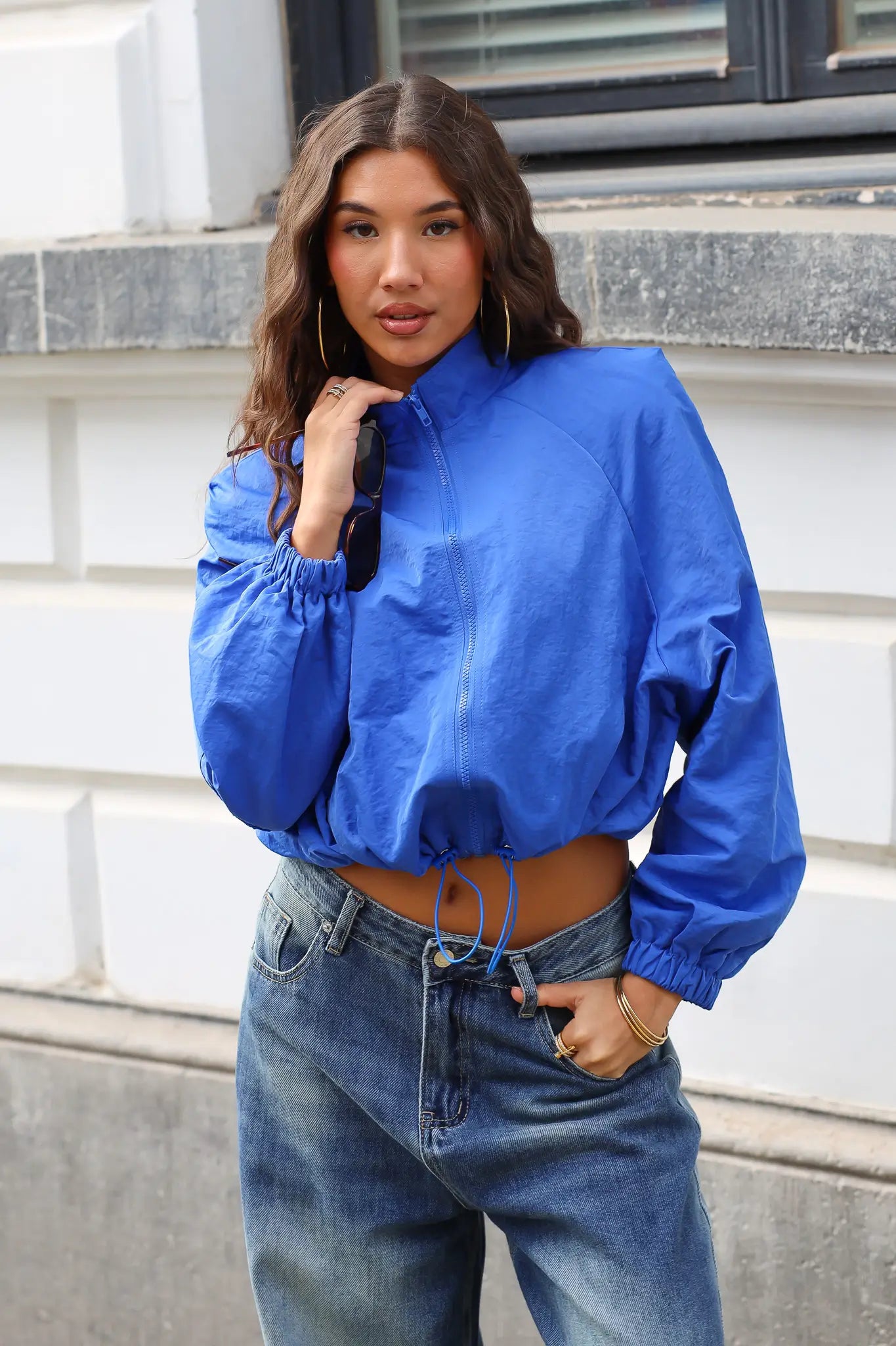Blauw track jacket met hoge kraag en ritssluiting, gedragen met een blauwe jeans