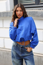Blauw track jacket met hoge kraag en ritssluiting, gedragen met een blauwe jeans