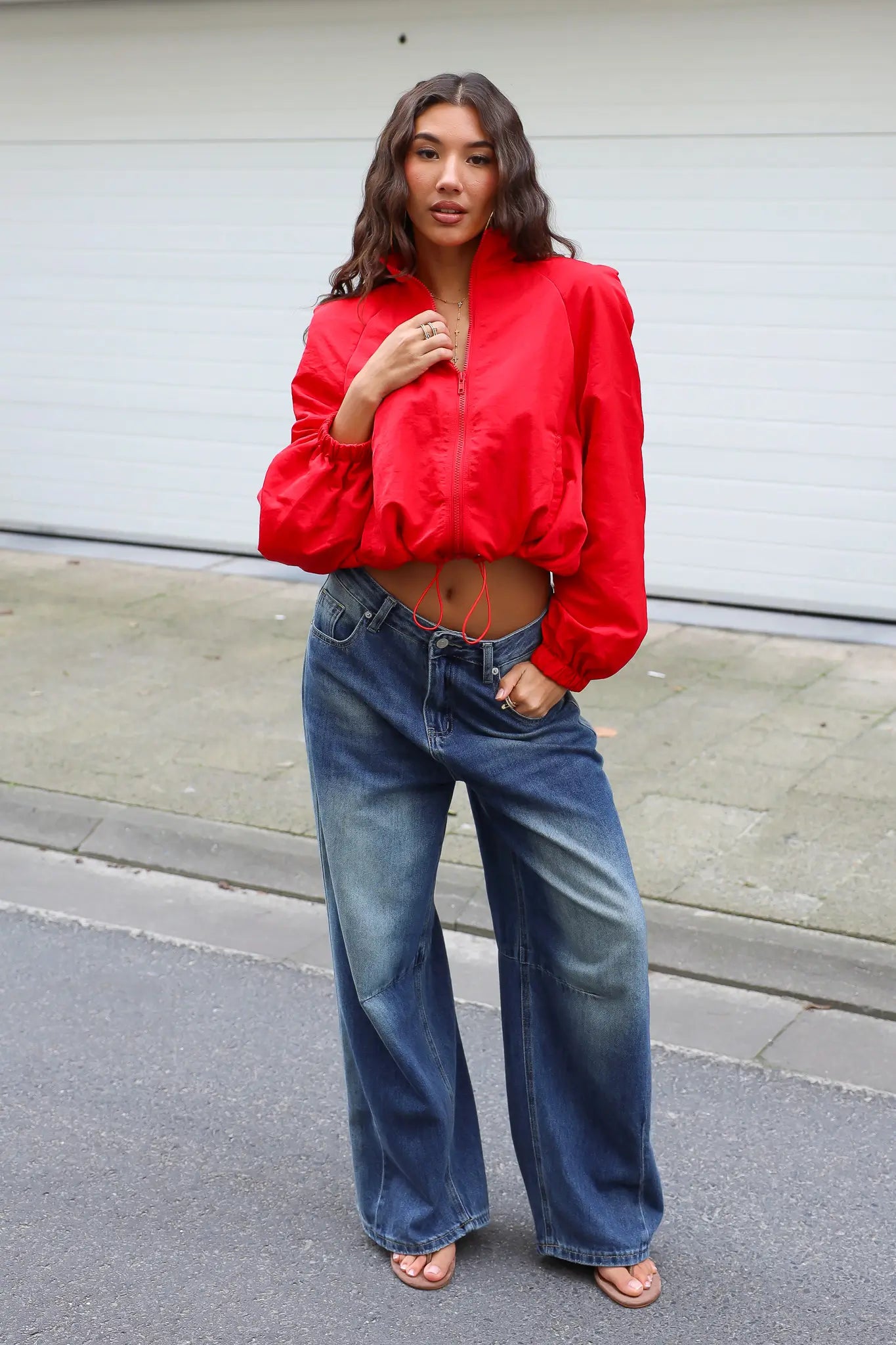 Rood track jasje gecombineerd met blauwe wide leg jeans voor een casual streetstyle outfit
