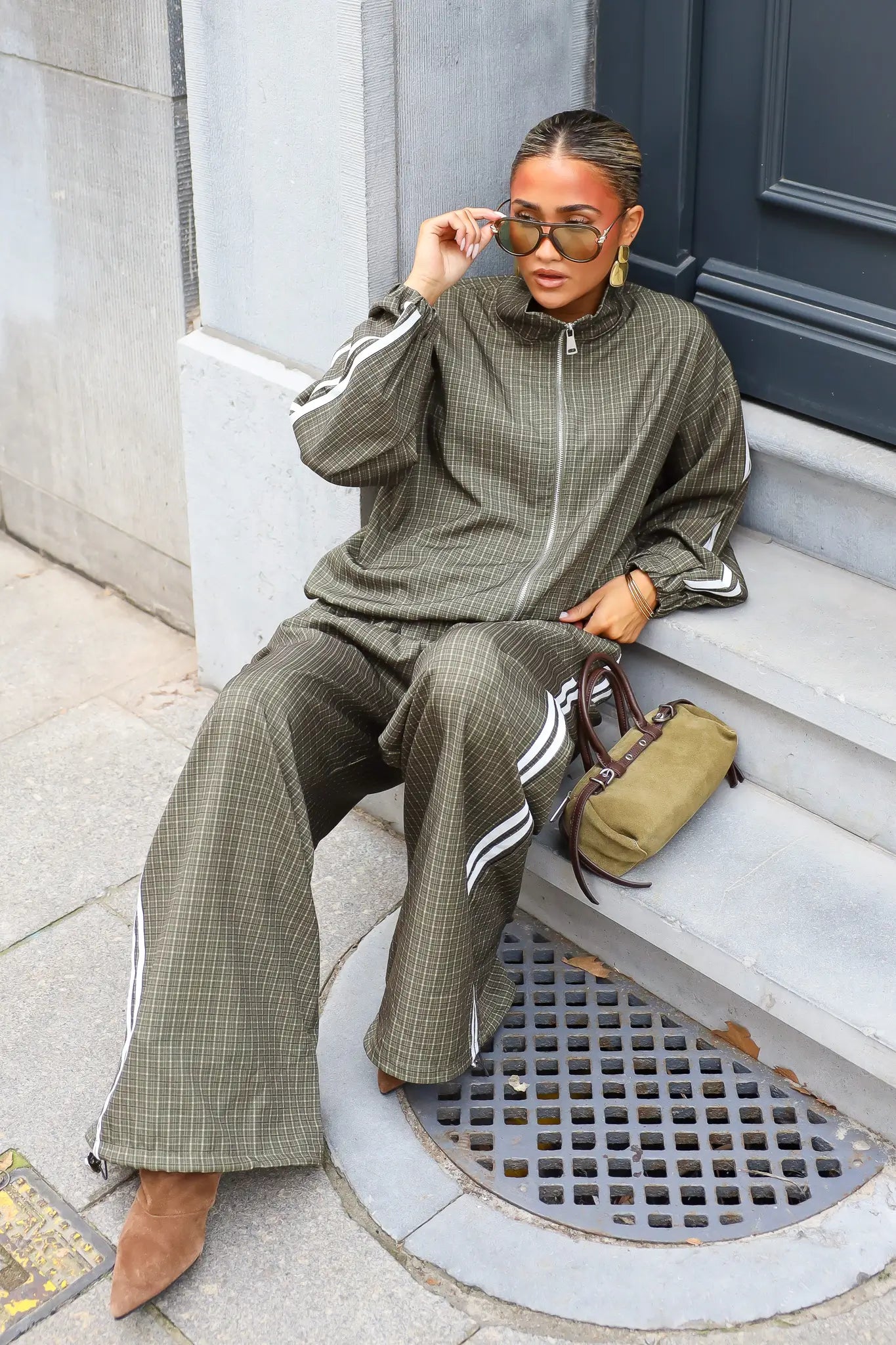 Dames tracksuit set olijfgroen met geruit patroon en wijde broek zittend op trap
