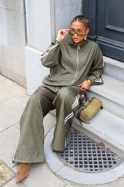 Dames tracksuit set olijfgroen met geruit patroon en wijde broek zittend op trap