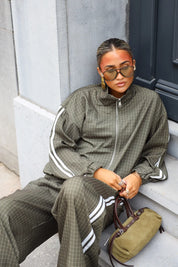 Geruite tracksuit dames met ritssluiting en witte strepen zittend