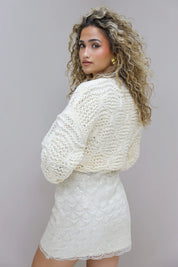 vrouw draagt creme trui met witte rok in studio