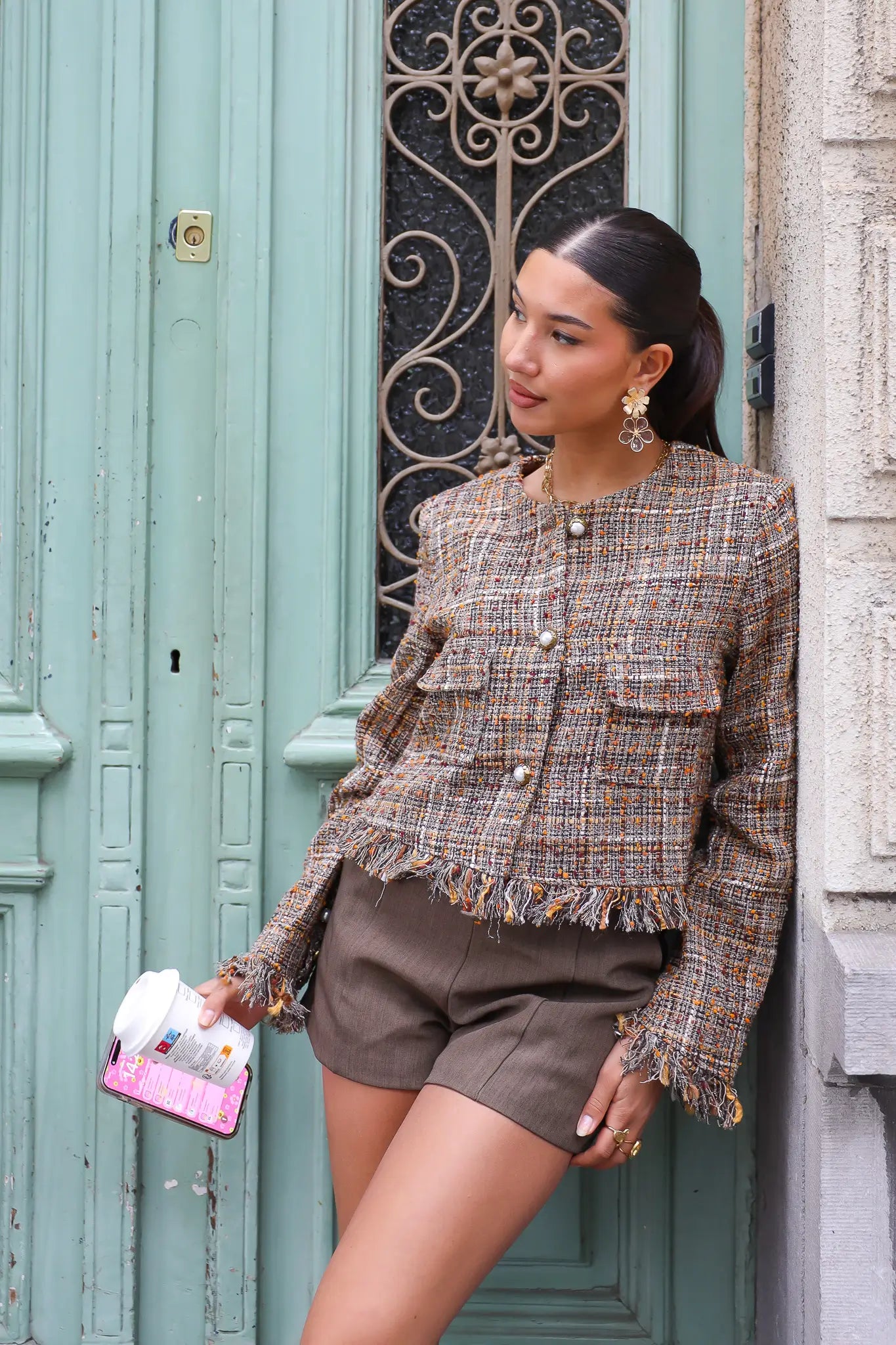 model draagt tweed cropped jasje bij mintgroene deur met koffie