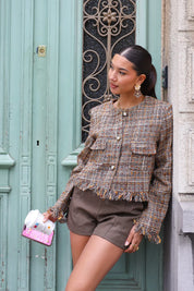 model draagt tweed cropped jasje bij mintgroene deur met koffie