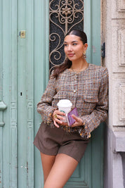 model houdt koffie vast in tweed jasje voor mintgroene deur