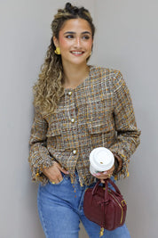 model met tweed jasje houdt koffie vast in studio