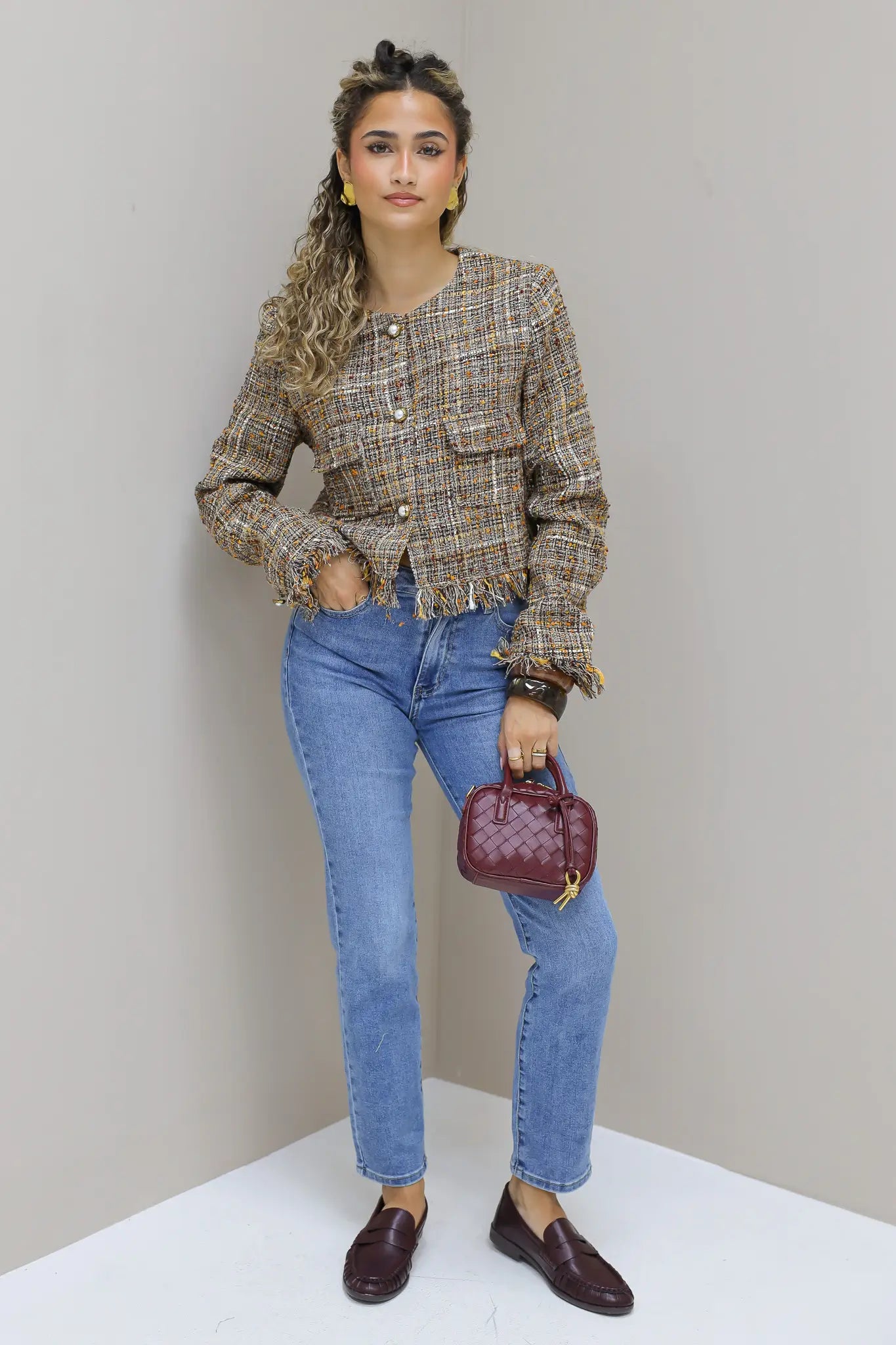model poseert recht vooruit in tweed jasje met jeans