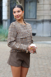 model staat volledig in beeld met tweed jasje en jeans