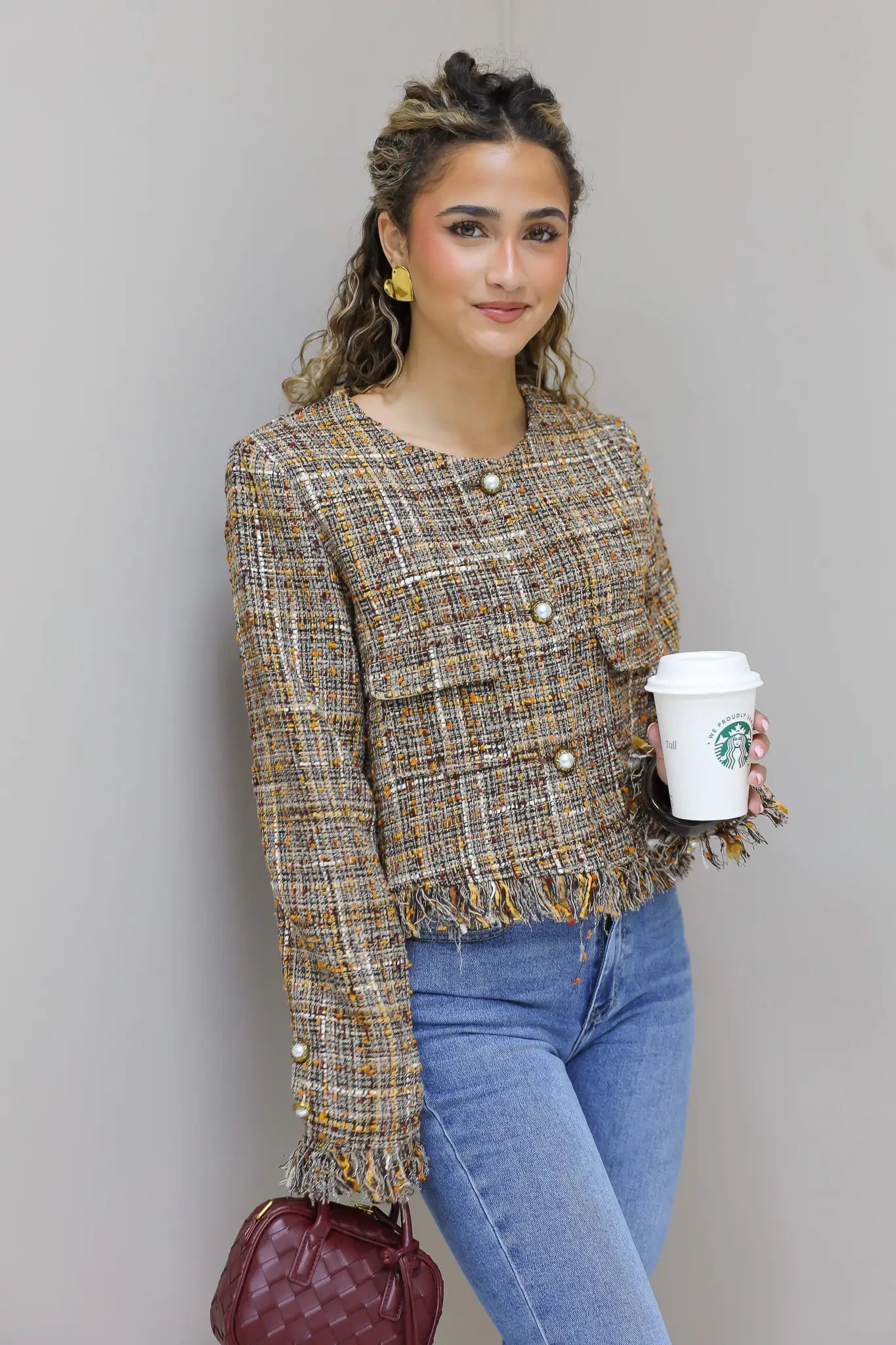 model staat met handen in zakken in tweed jasje en jeans