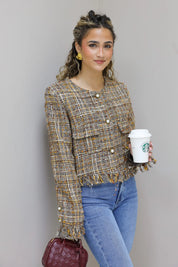 model staat met handen in zakken in tweed jasje en jeans