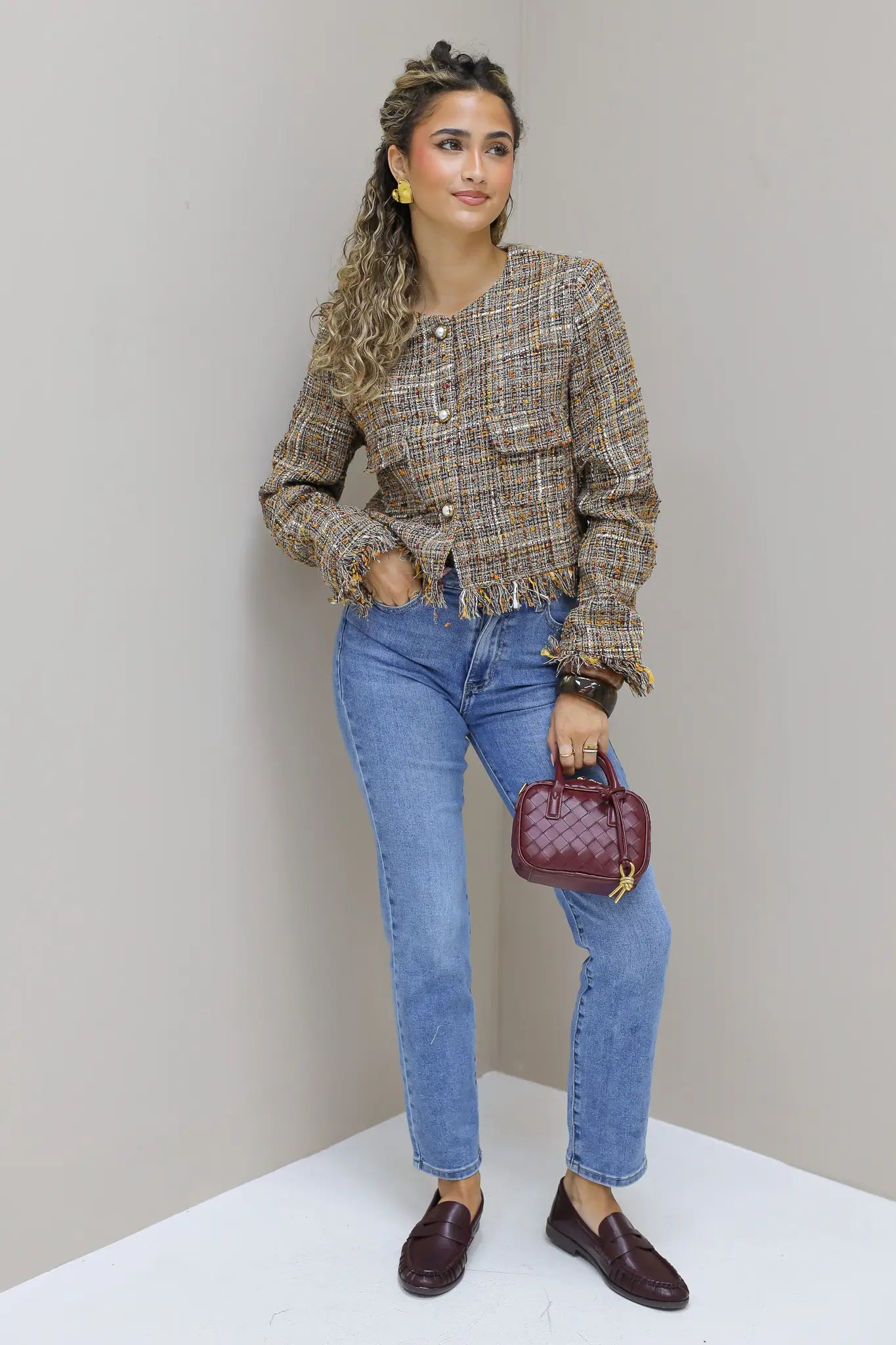 model staat rechtop in studio met tweed jasje en jeans