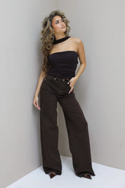 Model poseert tegen grijze muur, ontspannen houding