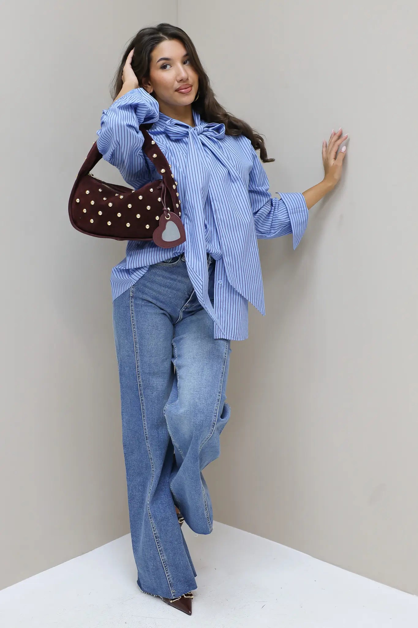 model draagt lichtblauwe wide leg jeans met gestreepte blouse