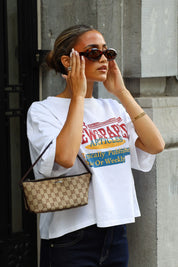 Wit oversized T-shirt met newspaper print gecombineerd met een zwarte jeans en beige tas met patroon