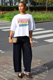 Wit T-shirt met kleurrijke newspaper opdruk gedragen bij een donkere wide leg jeans en zwarte schoenen