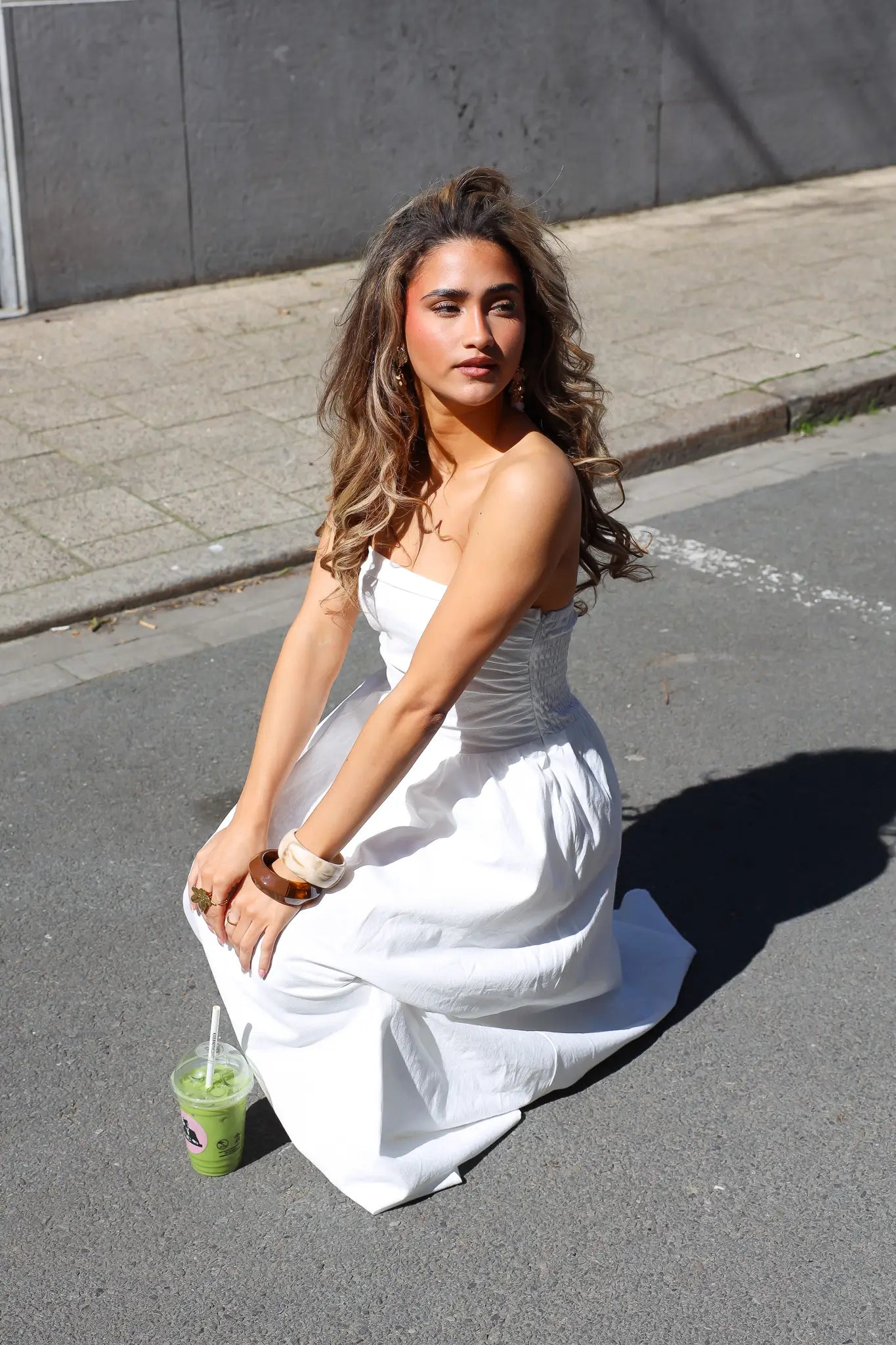 Witte strapless maxi jurk dames zittend op straat