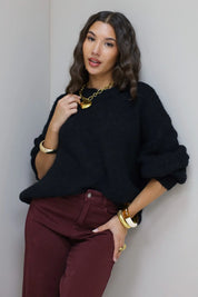 Model draagt zwarte cropped trui met bordeaux broek en hakken