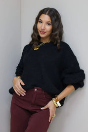 Model poseert in zwarte cropped trui met bordeaux broek