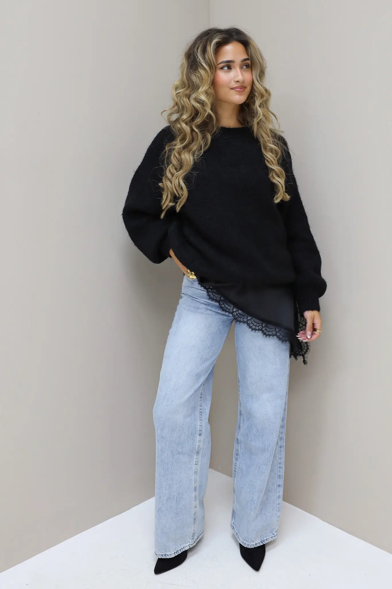 Model met zwarte cropped trui en lichtblauwe jeans