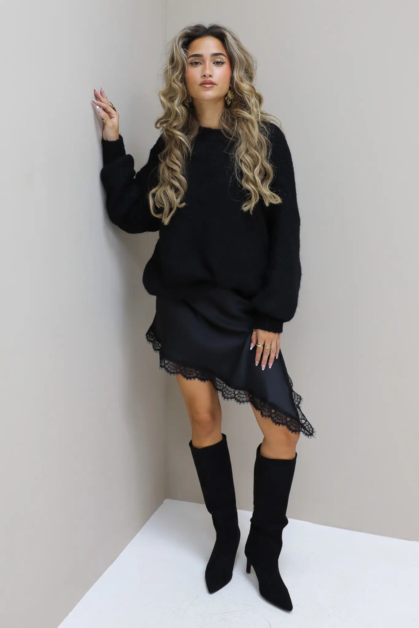 Model met zwarte cropped trui, kort rokje en hoge laarzen